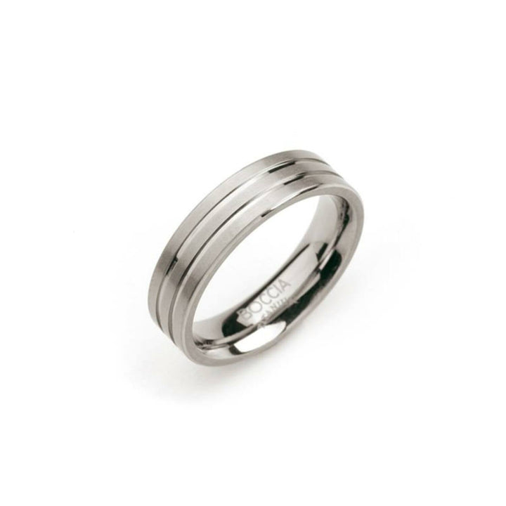 De Boccia Titanium Ring 0101-02 is een strakke titanium ring met een dubbel groefontwerp. De merknaam is subtiel gegraveerd op de binnenband en wordt elegant weergegeven tegen een effen witte achtergrond.