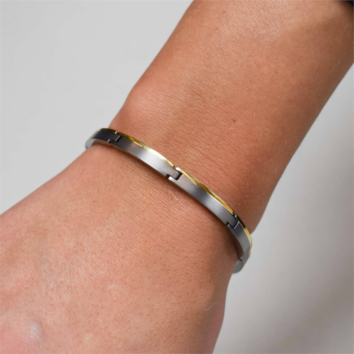 De Boccia Titanium Armband Bicolor 03025-02 siert de pols op elegante wijze en heeft een tweekleurig ontwerp in zilver en goud met in elkaar grijpende segmenten. Hierdoor ontstaat een strakke, moderne look die schittert tegen een effen achtergrond.