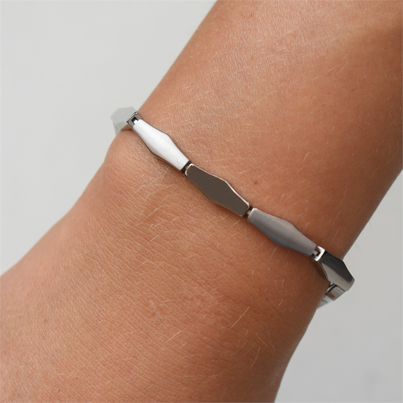 Een close-up van een pols met de Boccia Titanium Armband 03039-01, met gladde, hoekige schakels en een gepolijste afwerking van duurzaam materiaal, op een effen witte achtergrond.