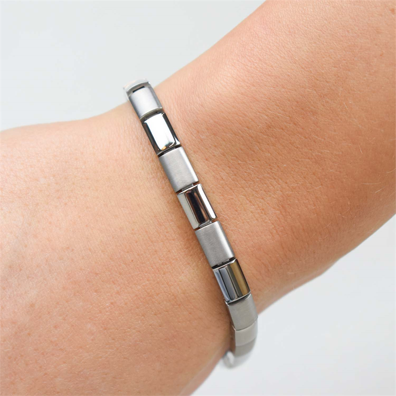 Een close-up van een pols met de Boccia Titanium Armband 0313-01: een stijlvol, zilverkleurig titanium armbandje met gesegmenteerde schakels en een gladde, glanzende afwerking van Boccia.