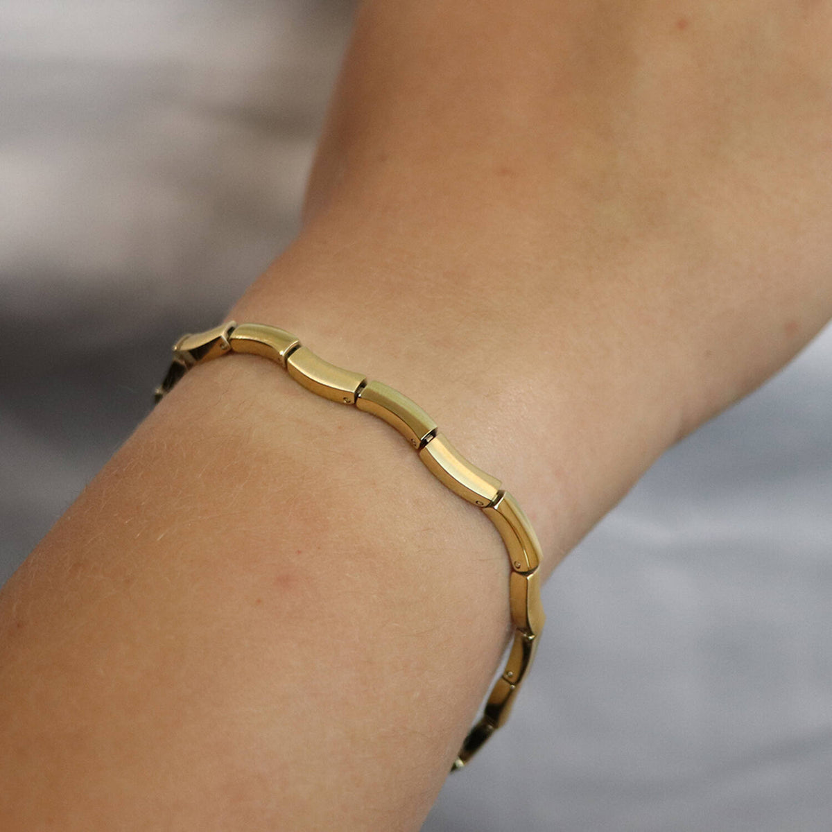 Een Boccia Titanium Armband gp 0370-06 met gladde, gebogen rechthoekige schakels wordt om de pols gedragen tegen een zachte, wazige achtergrond. Merk: Boccia. EAN: 4040066271064.
