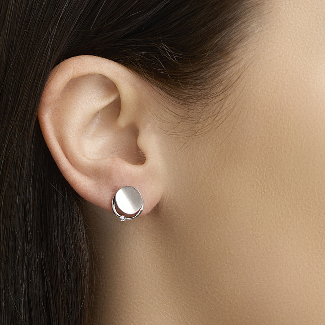 Close-up van het oor van een vrouw met Van der Kooij Collectie oorknoppen zirkonia poli/mat zilver gerhodineerd. Haar donkere haar is naar achteren gestoken, waardoor deze elegante dames sieraden goed uitkomen tegen haar gladde, lichtgetinte huid.