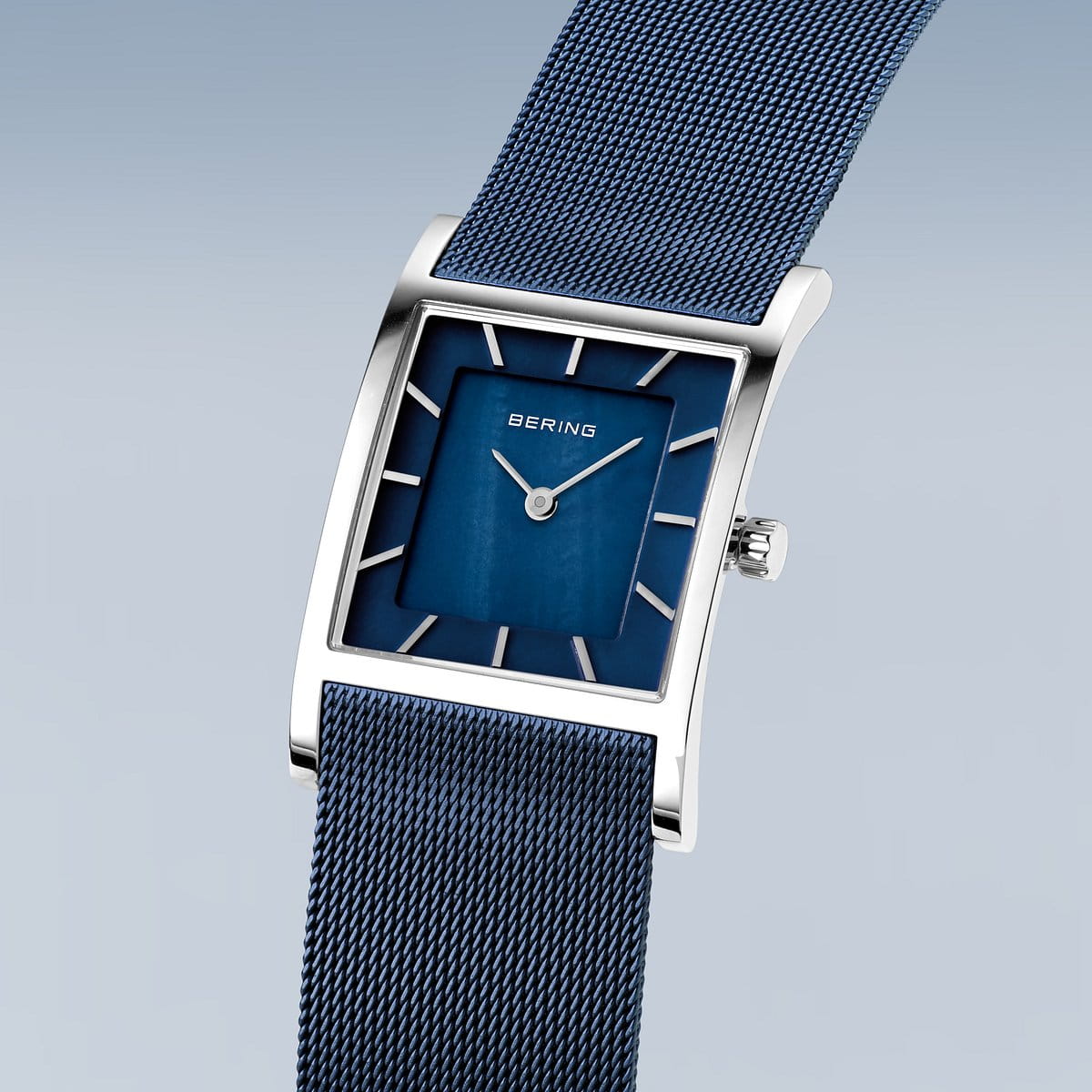 Het Bering Dameshorloge 10426-307-S heeft een strak, rechthoekig design met een blauwe wijzerplaat, zilveren uurmarkeringen en duurzaam Saffierglas. Het beschikt over een blauwe mesh band, zilveren kast met een kroon aan de rechterkant en een nauwkeurig Quartz uurwerk. Het merk Bering wordt elegant weergegeven op de wijzerplaat.