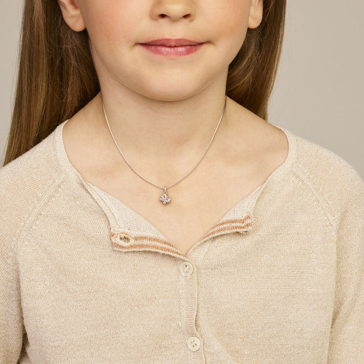 Een jong meisje draagt een beige vest en een Van der Kooij Collectie hanger vlinder zilver gerhodineerd, zachtjes glimlachend. Het beeld is cropped van schouders tot kin en is ideaal voor kinderen vrouwen.