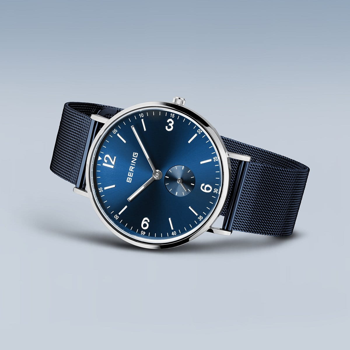 De Bering heren horloge blauw 14040-307 heeft een minimalistisch ontwerp met een blauwe mesh band, blauwe wijzerplaat, zilveren details, roestvrijstalen kast, kleine secondewijzer en een quartz uurwerk.