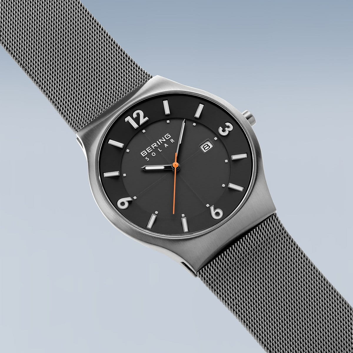 De Bering 14440-077 is een strak minimalistisch horloge met een zilveren meshband, donkere wijzerplaat, zilveren uurmarkeringen, oranje secondewijzer en Saffierglas-bescherming. Het maakt gebruik van Solar-technologie en toont de datum op 3 uur op een gradiëntblauwe achtergrond.