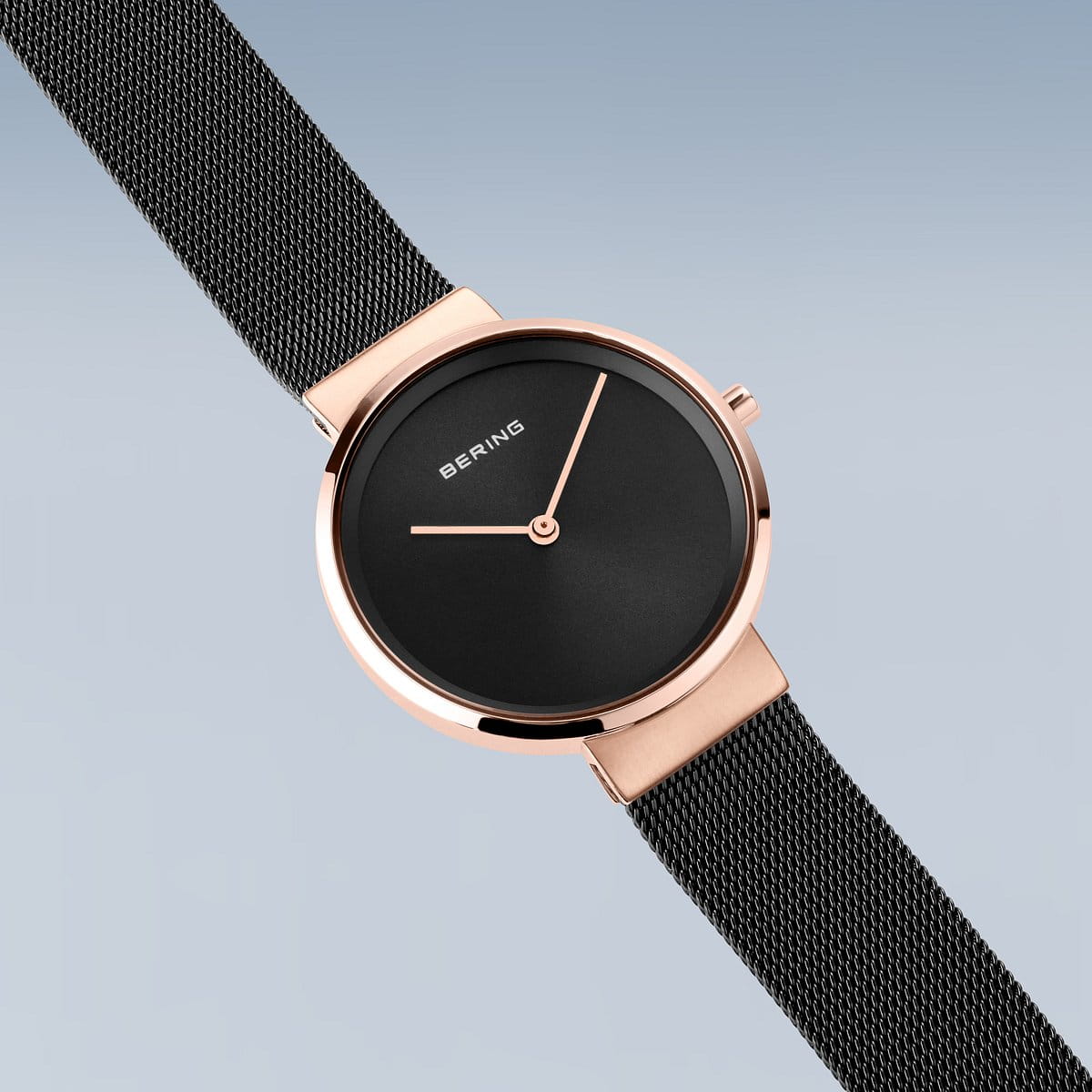 Het Bering dameshorloge model 14531-166 toont een minimalistisch horloge met een roestvrijstalen kast, strakke zwarte wijzerplaat, slanke gouden wijzers aangedreven door Quartz-uurwerk, en aangevuld met een zwarte mesh band. De serene lichtblauwe achtergrond accentueert de BERING-branding op de wijzerplaat.