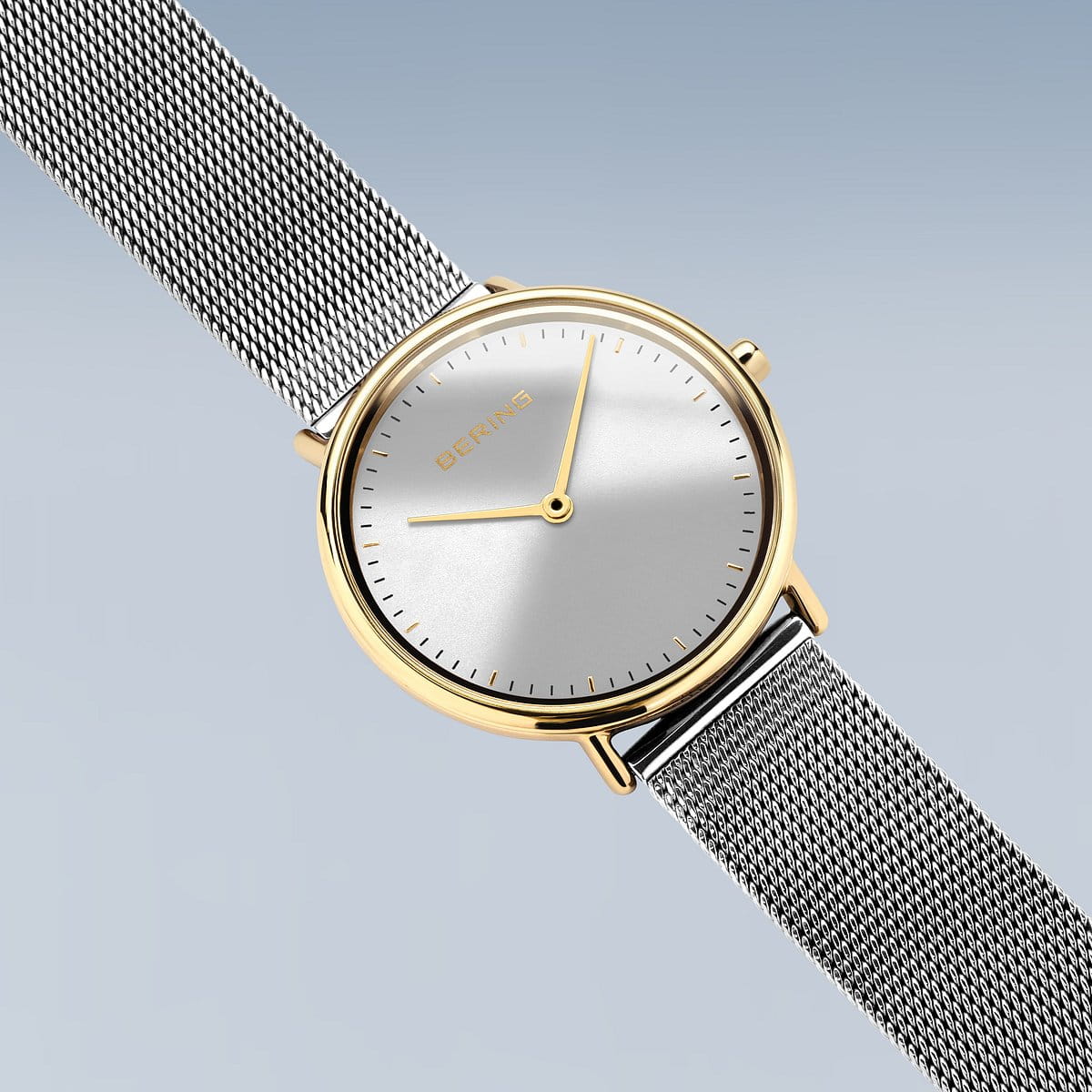 Het Bering 15729-010 dameshorloge straalt elegantie uit met zijn minimalistische design, met een ronde witte wijzerplaat versierd met gouden accenten, strakke uur- en minutenwijzers en een stijlvolle meshband. De merknaam wordt elegant weergegeven op de wijzerplaat tegen een gradiëntblauwe achtergrond in een roestvrijstalen kast.