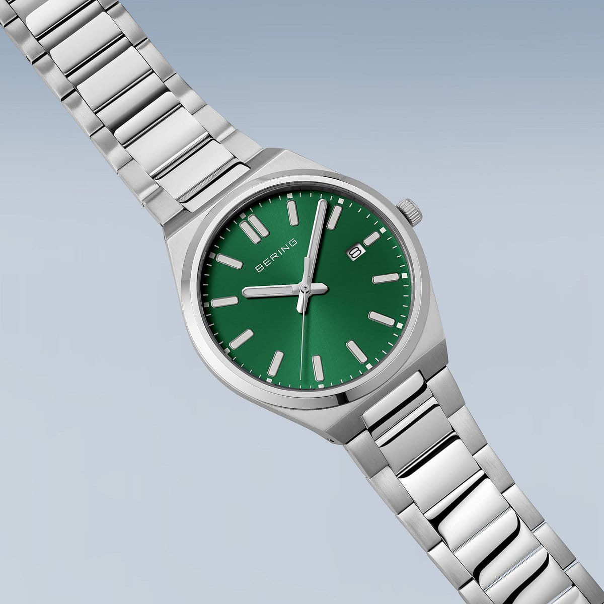 De Bering heren horloge groene wijzerplaat 17639-708 heeft een groene wijzerplaat, zilveren markers en wijzers, quartz uurwerk en datumweergave op 3 uur, allemaal van Bering, tegen een lichtblauwe gradiënt achtergrond.