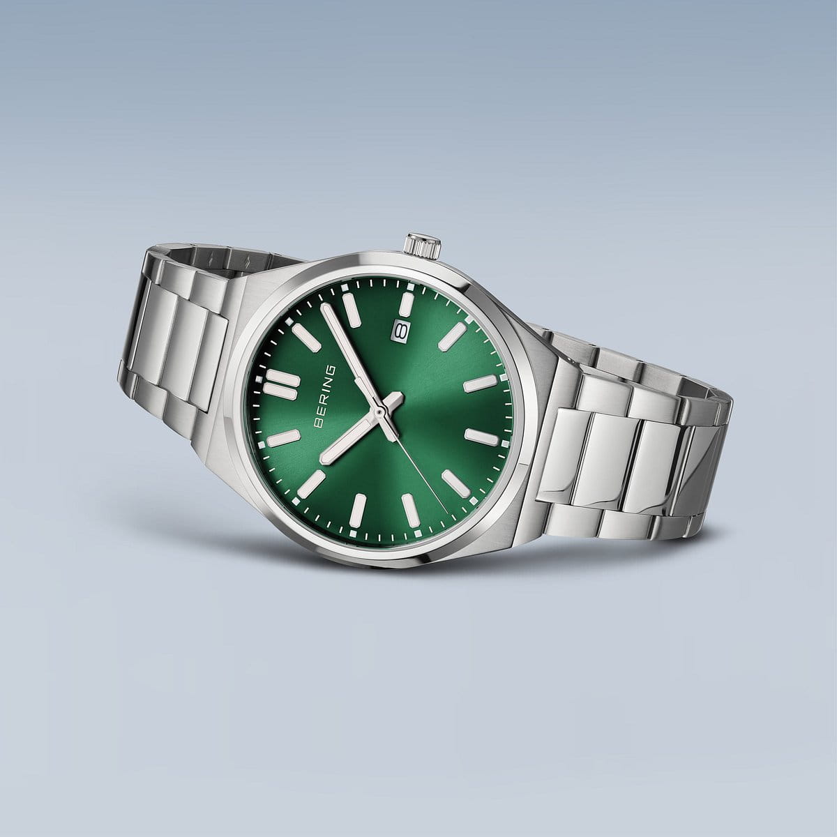 Het Bering heren horloge 17639-708 heeft een zilverkleurige metalen band, een groene wijzerplaat met witte uurmarkeringen en wijzers en een datumvenster op 3 uur. Dit BERING horloge wordt weergegeven op een lichtblauwe achtergrond.