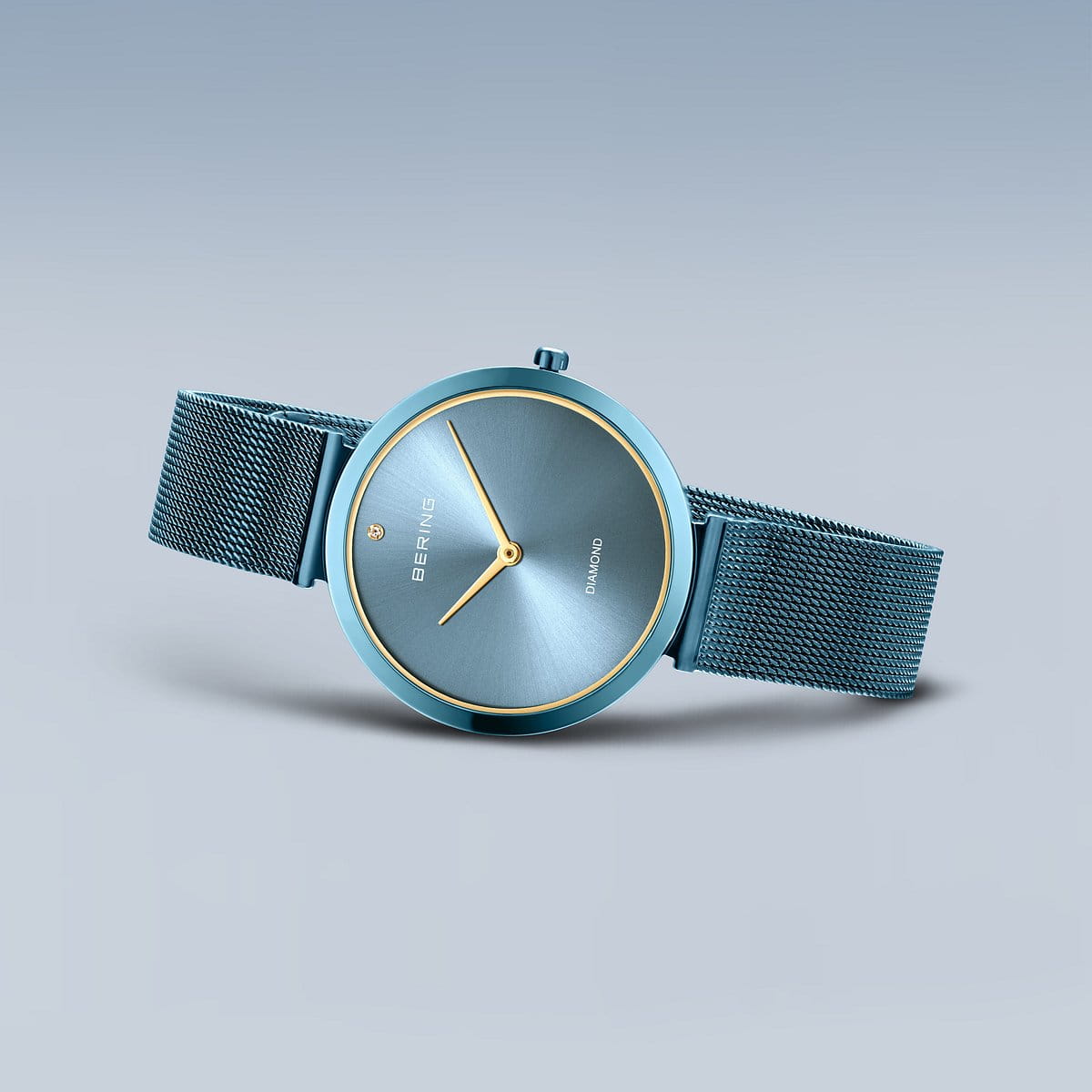 De Bering dameshorloge 18132-Charity1 heeft een blauwe mesh band, minimalistische blauwe wijzerplaat, gouden markers en wijzers en duurzaam saffierglas. Het Bering-logo verschijnt op de wijzerplaat op een lichtblauwe achtergrond met kleurverloop.