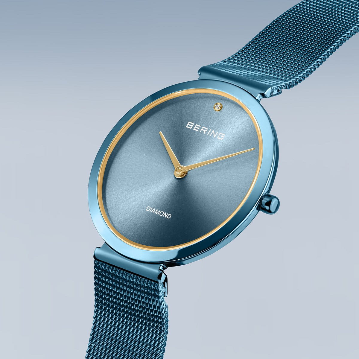 De Bering dames horloge blauwe wijzerplaat - 18132-Charity1 heeft een blauwe mesh band, blauwe wijzerplaat, gouden wijzers, saffierglas en een diamant op 12 uur, afgebeeld op een lichtblauwe achtergrond met kleurverloop.