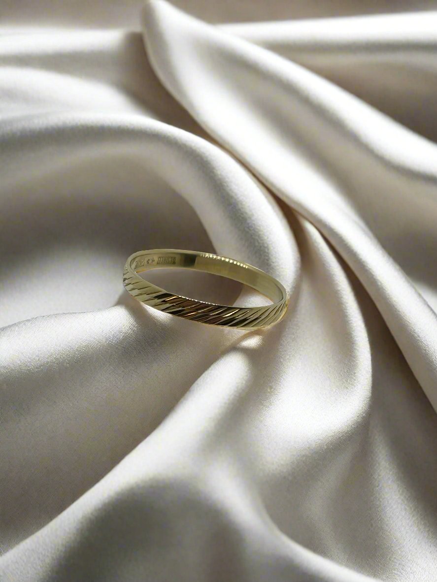 Vintage gouden ring van 14k met een gestructureerde band op een satijnen ondergrond.