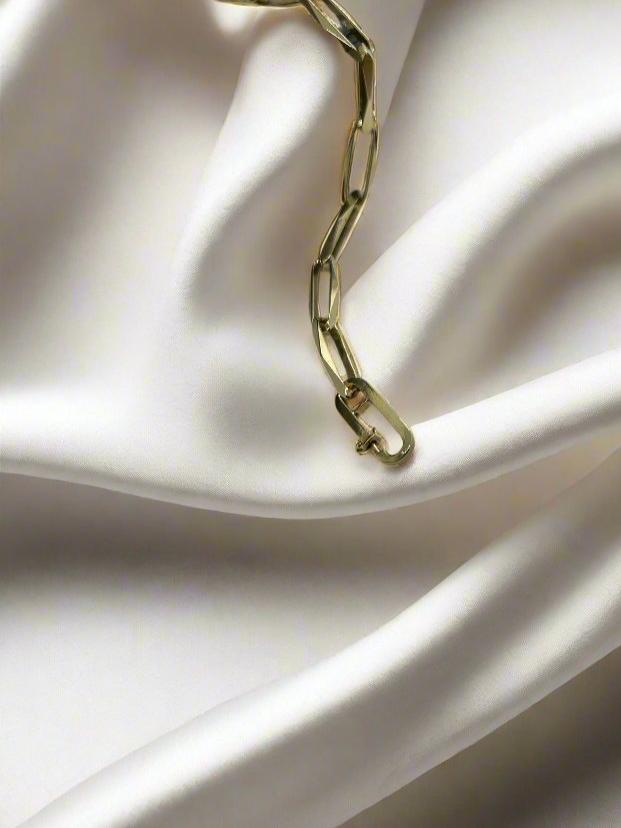 De 14k Vintage Gouden Armband Closed Forever van Juwelier van der Kooij rust elegant op een gladde, witte stof, waarbij de glanzende ketting zachte vouwen creëert die elegantie en eenvoud oproepen.