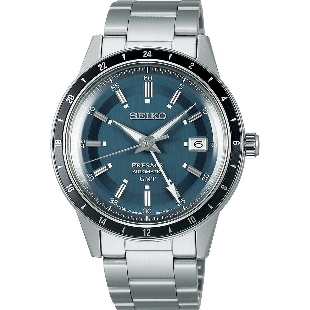 Seikos Presage herenhorloge, model SSK009J1, heeft een roestvrijstalen band en een blauwe wijzerplaat met zilveren en witte uurmarkeringen. Het heeft een datumvenster op 3 uur, een zwarte 24-uurs bezel en het midden van de wijzerplaat toont een subtiel waaierpatroon dat het verfijnde ontwerp benadrukt.