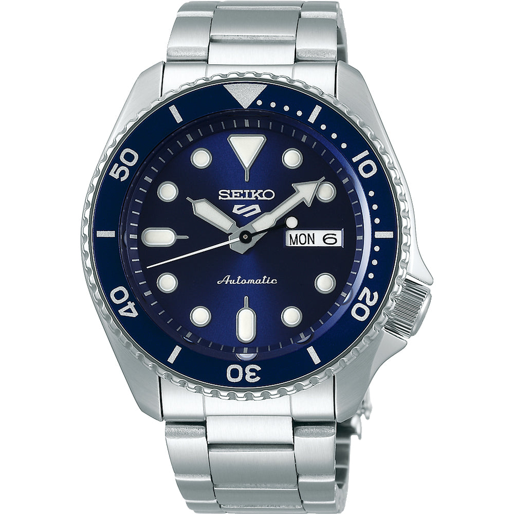 Het Seiko 5 Sports herenhorloge SRPD51K1 is voorzien van een automatisch uurwerk, een roestvrijstalen band, een blauwe wijzerplaat, witte uurmarkeringen, dag-datumaanduiding, draaibare lunette met minutenmarkeringen en lichtgevende wijzers.