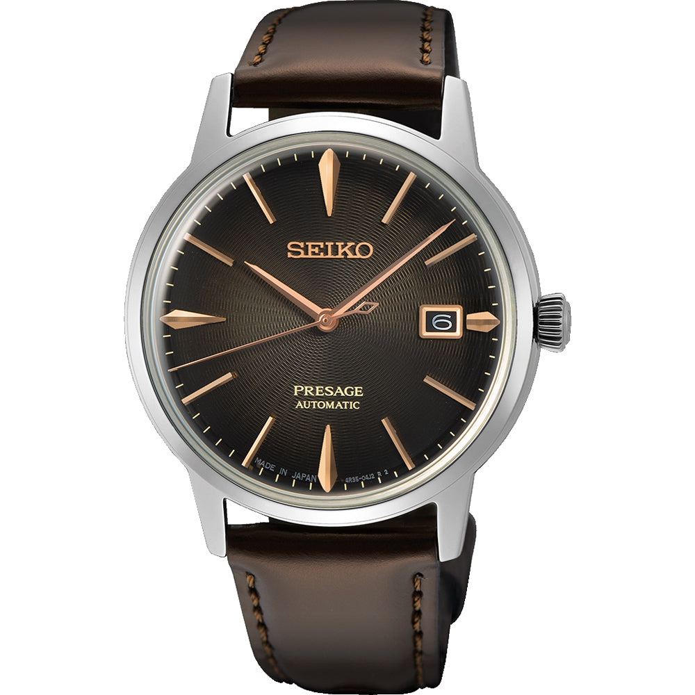 De Seiko Presage herenhorloge SRPJ17J1 heeft een automatisch uurwerk, met een donkerbruine leren band en een bruine wijzerplaat met gouden markeringen en wijzers. Het bevat een datumvenster op 3 uur, ingekapseld in zilver en beschermd door Hardlex mineraalglas, wat het klassieke ontwerp belichaamt.