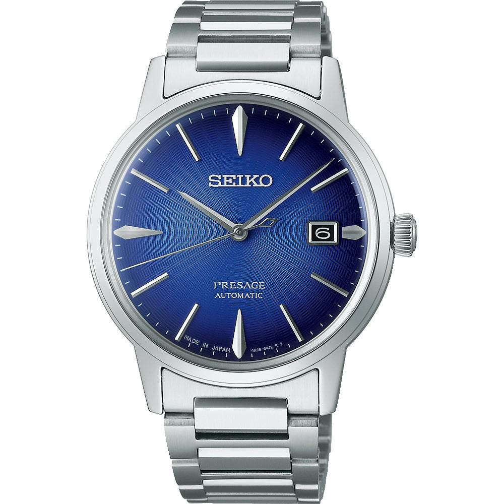 De Seiko Presage SRPJ13J1 heeft een roestvrijstalen kast en een opvallende blauwe sunburst wijzerplaat. Zilveren uurmarkeringen en wijzers versterken de elegantie, met een datumvenster op 3 uur. Made in Japan staat trots afgebeeld onderaan de wijzerplaat.