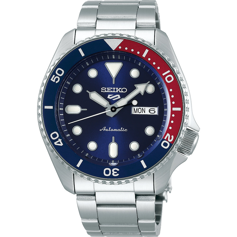 De Seiko 5 Sports herenhorloge SRPD53K1 van Seiko heeft een automatisch uurwerk, roestvrijstalen band, blauwe wijzerplaat met witte indexen, blauwrode lunette en is waterdicht. Dag- en datumaanduiding op 3 uur positie.