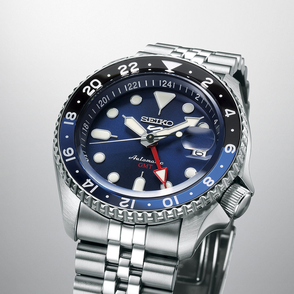 Het Seiko 5 Sports SSK003K1 horloge van Seiko heeft een blauw/zwarte lunette, blauwe wijzerplaat, lichtgevende markeringen/wijzers, automatisch uurwerk, datumvenster, rode GMT-wijzer en duurzame roestvrijstalen band. Het is waterbestendig tot 10ATM, perfect voor dagelijkse avonturen.