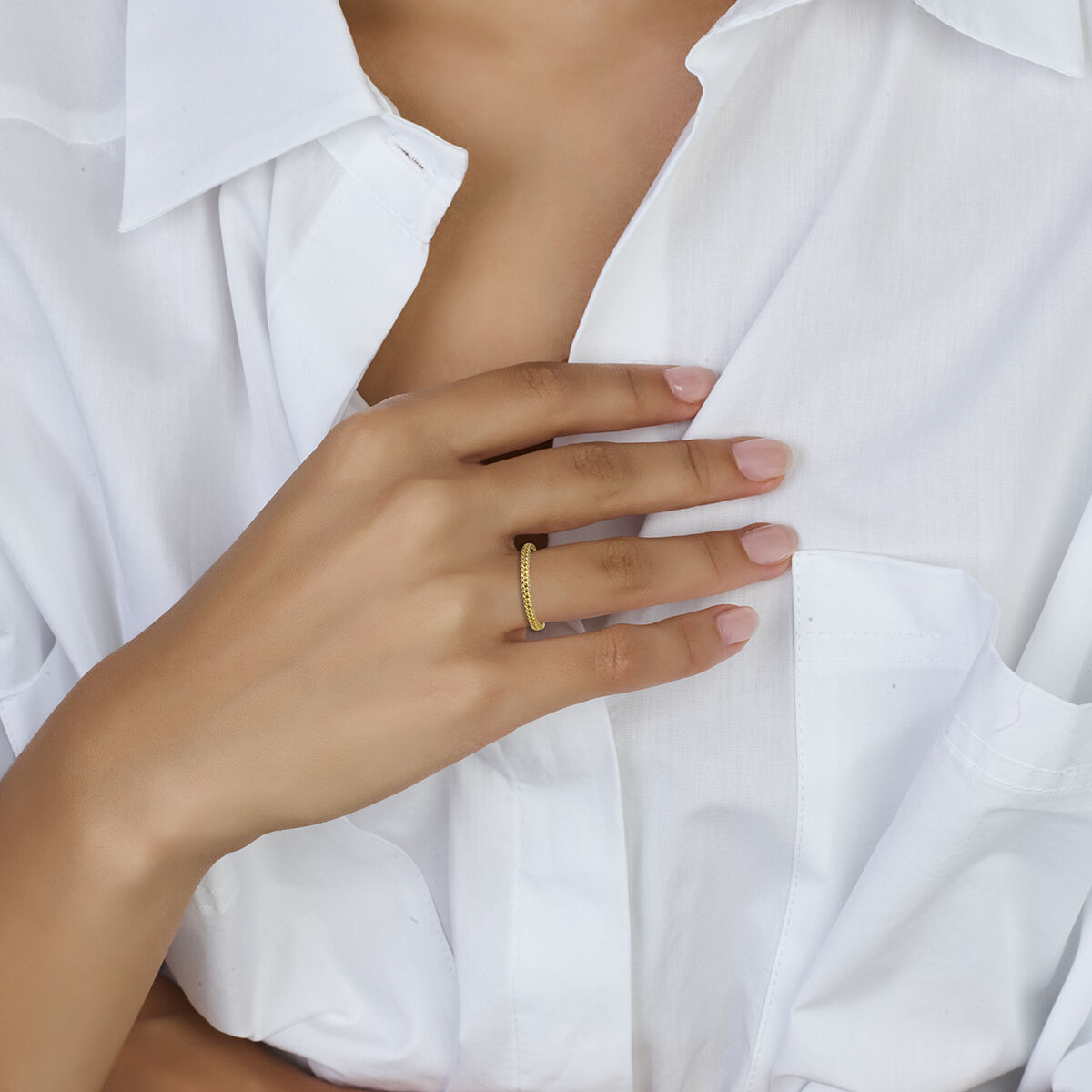 Een persoon in een wit overhemd met knoopsluiting raakt zachtjes zijn borst aan en toont de aanschuifring schakel 14K geelgoud van Van der Kooij Collectie-een subtiele ode aan tijdloze stijl en luxe sieraden.