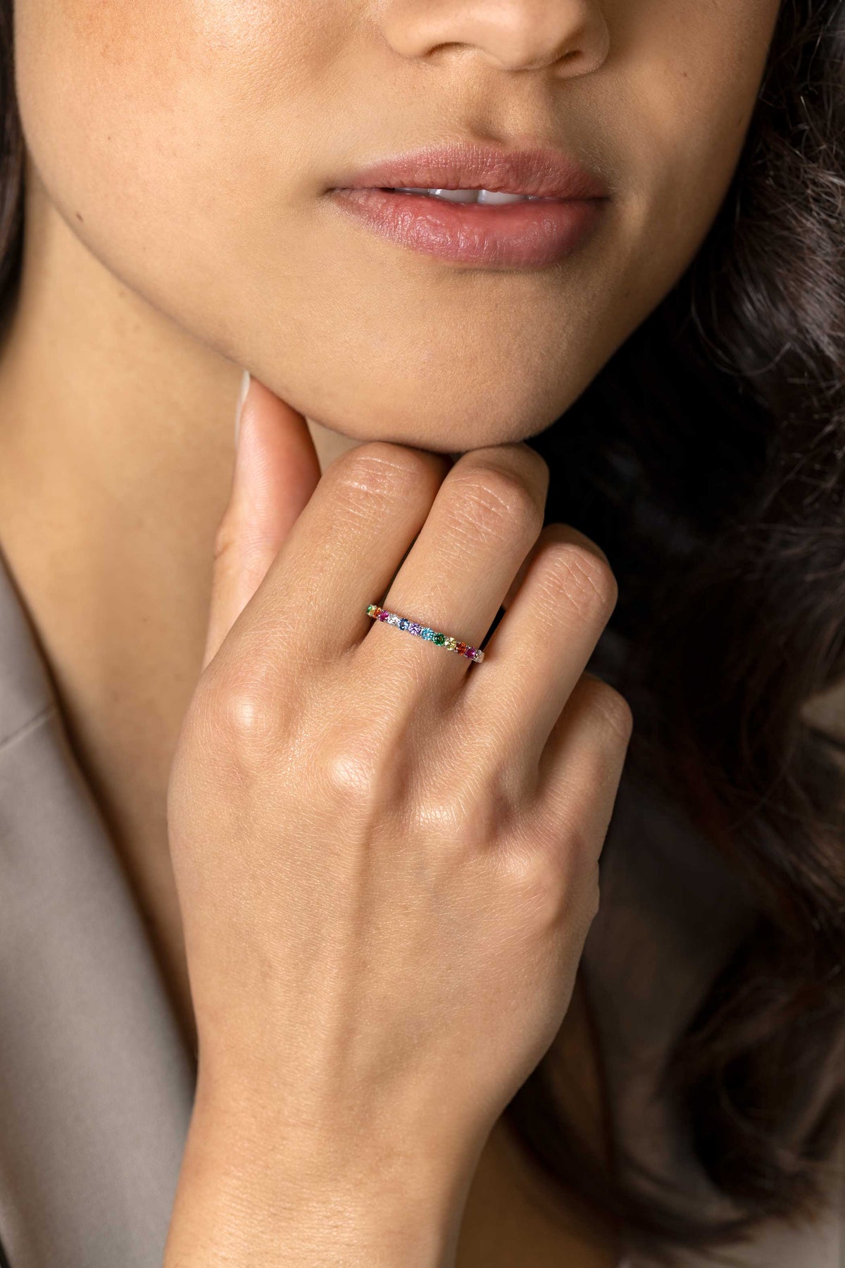 De hand van een vrouw rust tegen haar kin en toont de elegante Zinzi Ring Zilver Zir2486 met kleurstenen aan haar vinger. Alleen de onderste helft van haar gezicht is zichtbaar, wat de schoonheid van deze Zinzi creatie benadrukt.