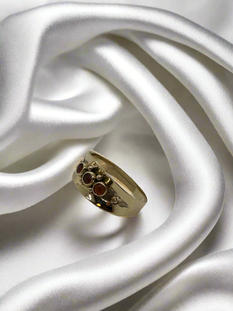 Vintage gouden ring van 14k met granaatstenen, gewicht 2.1 gram, op een satijnen ondergrond.