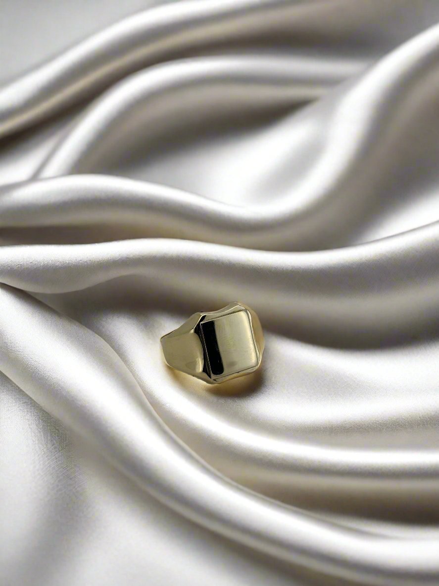 Vintage gouden ring van 14k met een gladde, geometrische vorm op een satijnen achtergrond.