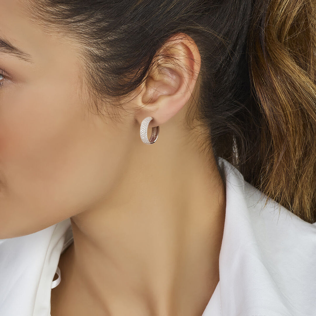 Close-up van een vrouw met bruin haar in een staart en witte blouse, die Van der Kooij Collectie klapoorringen zirkonia zilver gerhodineerd draagt. Perfecte fonkelende oorbellen voor stijlvolle dames.