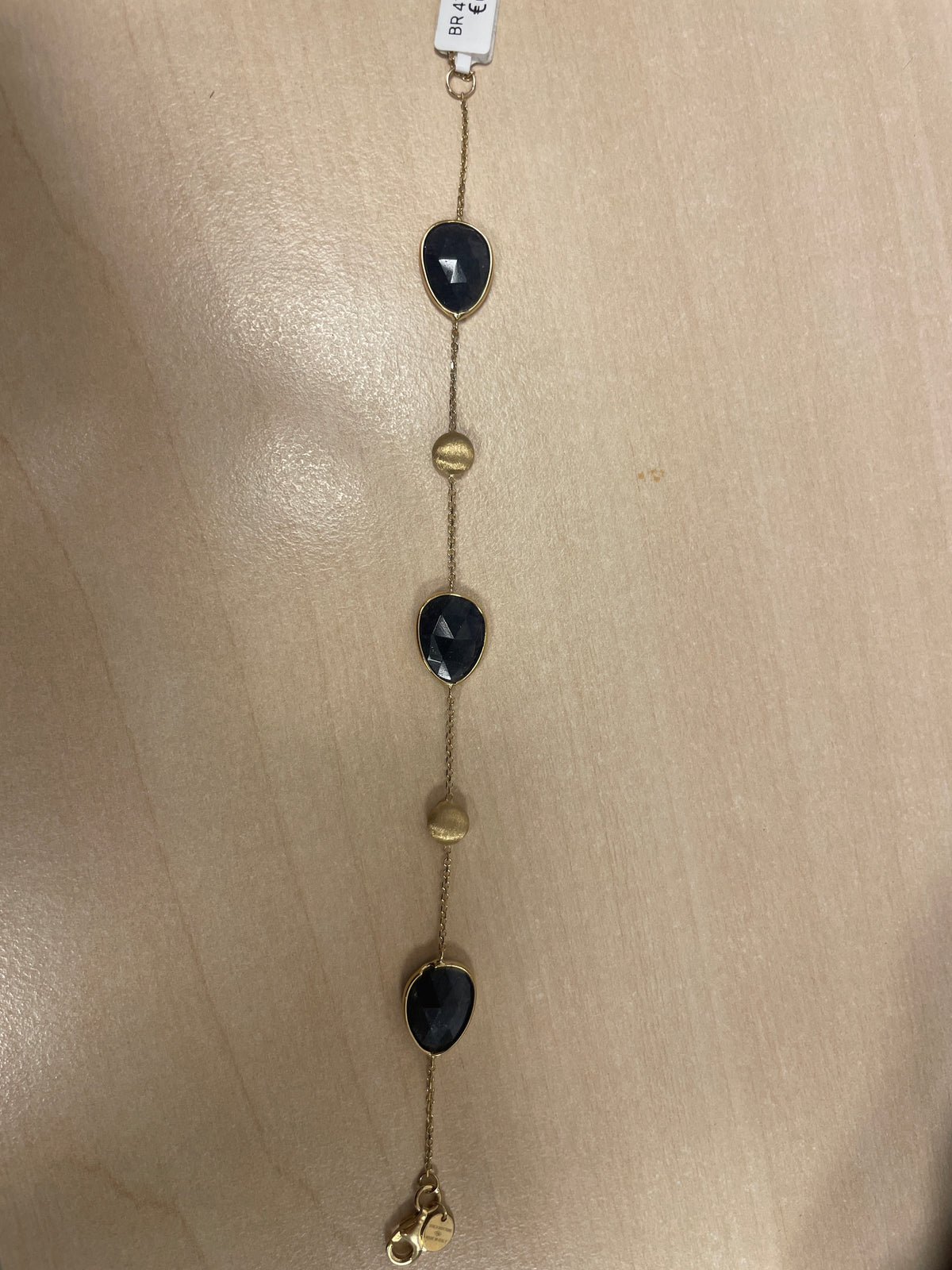 Gouden armband met zwarte en gouden edelstenen in een afwisselend patroon.