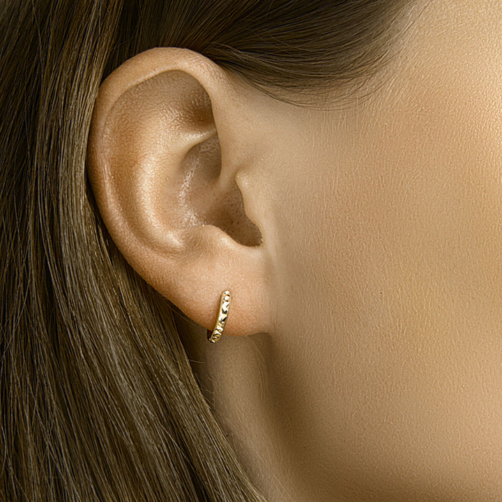 Een close-up van een vrouwenoor met steil bruin haar, met Van der Kooij Collectie klapoorringen gediamanteerd 14K geelgoud.