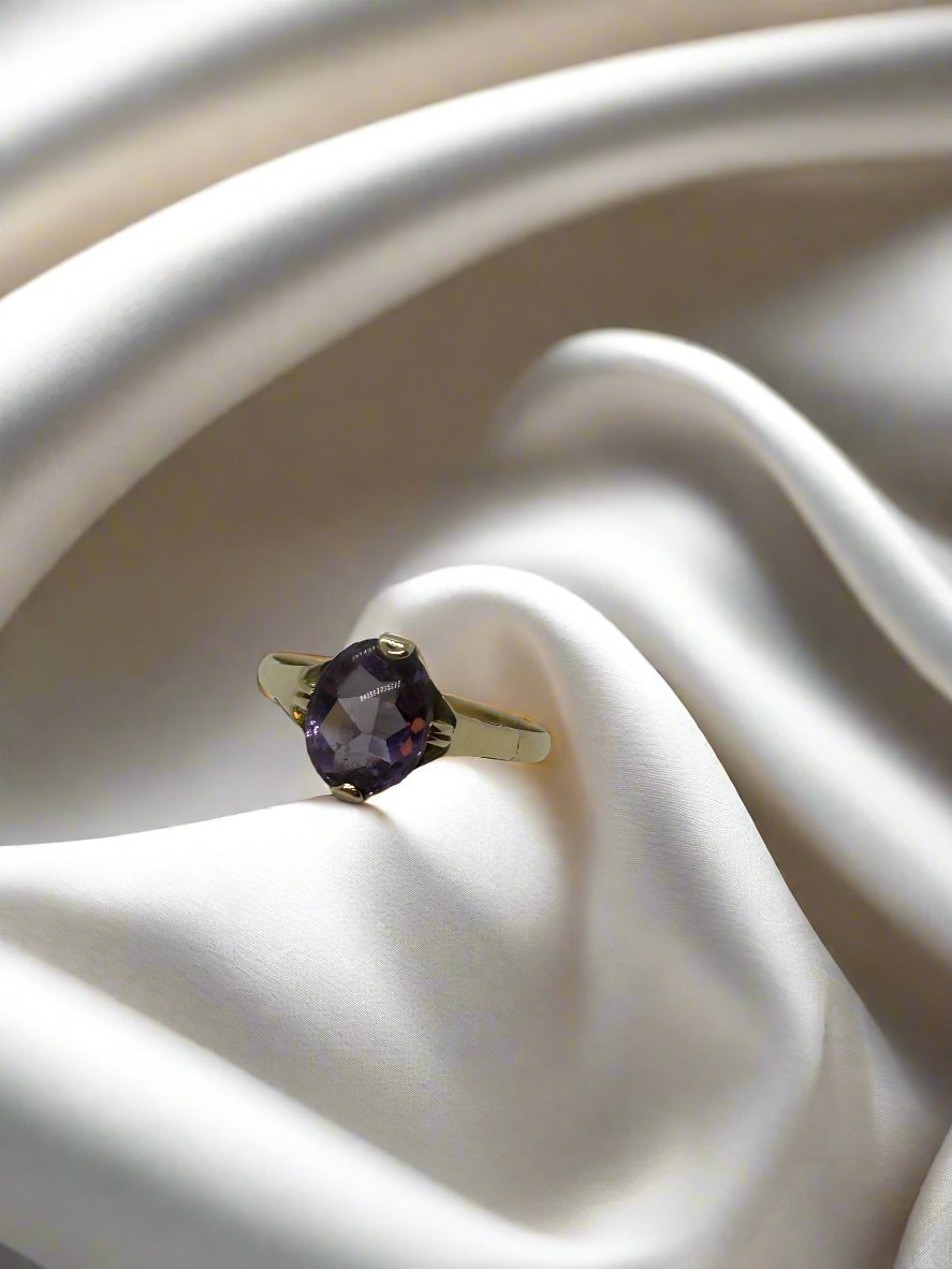Vintage gouden ring van 14k met een ovale amethist, afgewerkt met een glanzende, gladde band.