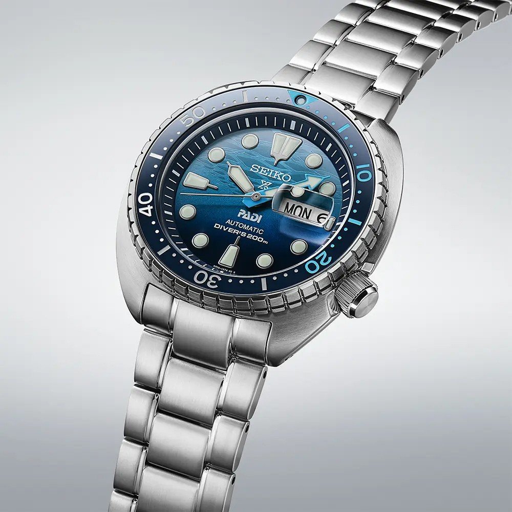 De Seiko Prospex SRPK01K1 is een automatisch duikhorloge voor heren met een roestvrijstalen band, een blauwe wijzerplaat met kleurverloop, lichtgevende markeringen, een dag-datumweergave en een lunette met minutenmarkering voor duiken. Het horloge combineert elegantie met de functionaliteit van een klassiek duikhorloge.