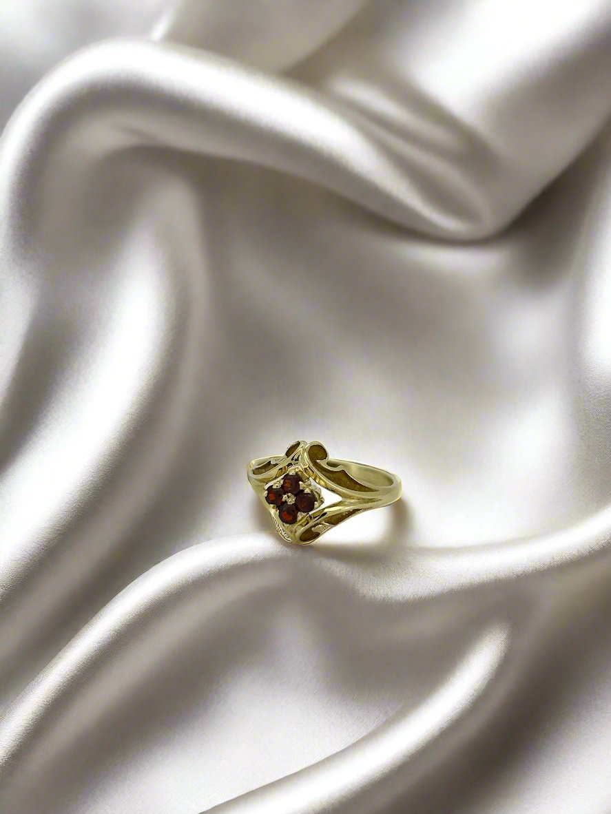 Geelgouden vintage ring met drie rode granaatstenen in een golvende setting.