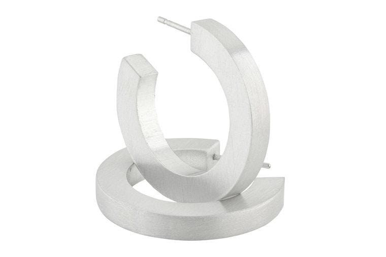 Zilveren creolen met een ronde, matte afwerking en een moderne, geometrische vorm.