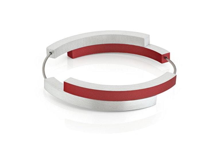 Armband met vier bogen, zilver en rood, met een strakke, moderne vormgeving.