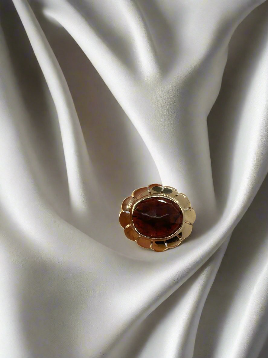 Een vintage gouden ring 14k ovale kwarts 3.5gr van Juwelier van der Kooij rust op een gladde, vloeiende witte stof, waardoor een opvallend contrast ontstaat tussen de levendige sieraden en de zachte achtergrond.