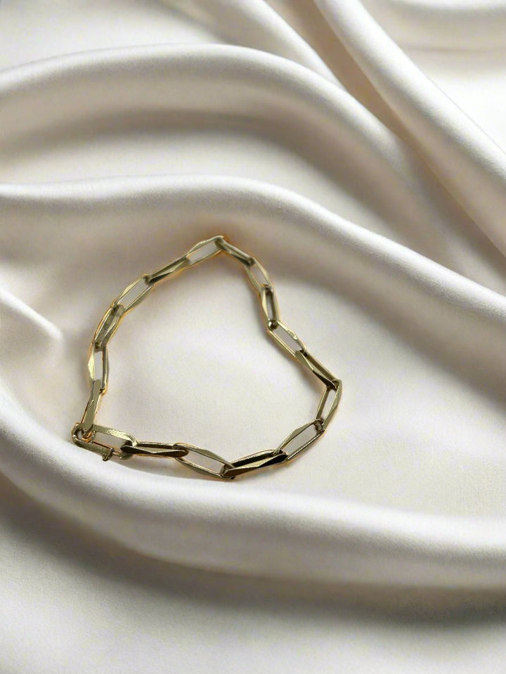 De 14k vintage gouden armband Closed Forever van Juwelier van der Kooij, weegt 7,4 gram, heeft rechthoekige schakels in de vorm van een hart op glad crèmekleurig satijn, wat een luxueuze vintage charme en een romantische esthetiek uitstraalt.