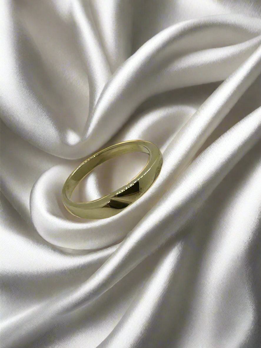 Vintage gouden ring van 14k met een gladde afwerking, geplaatst op een satijnen ondergrond.