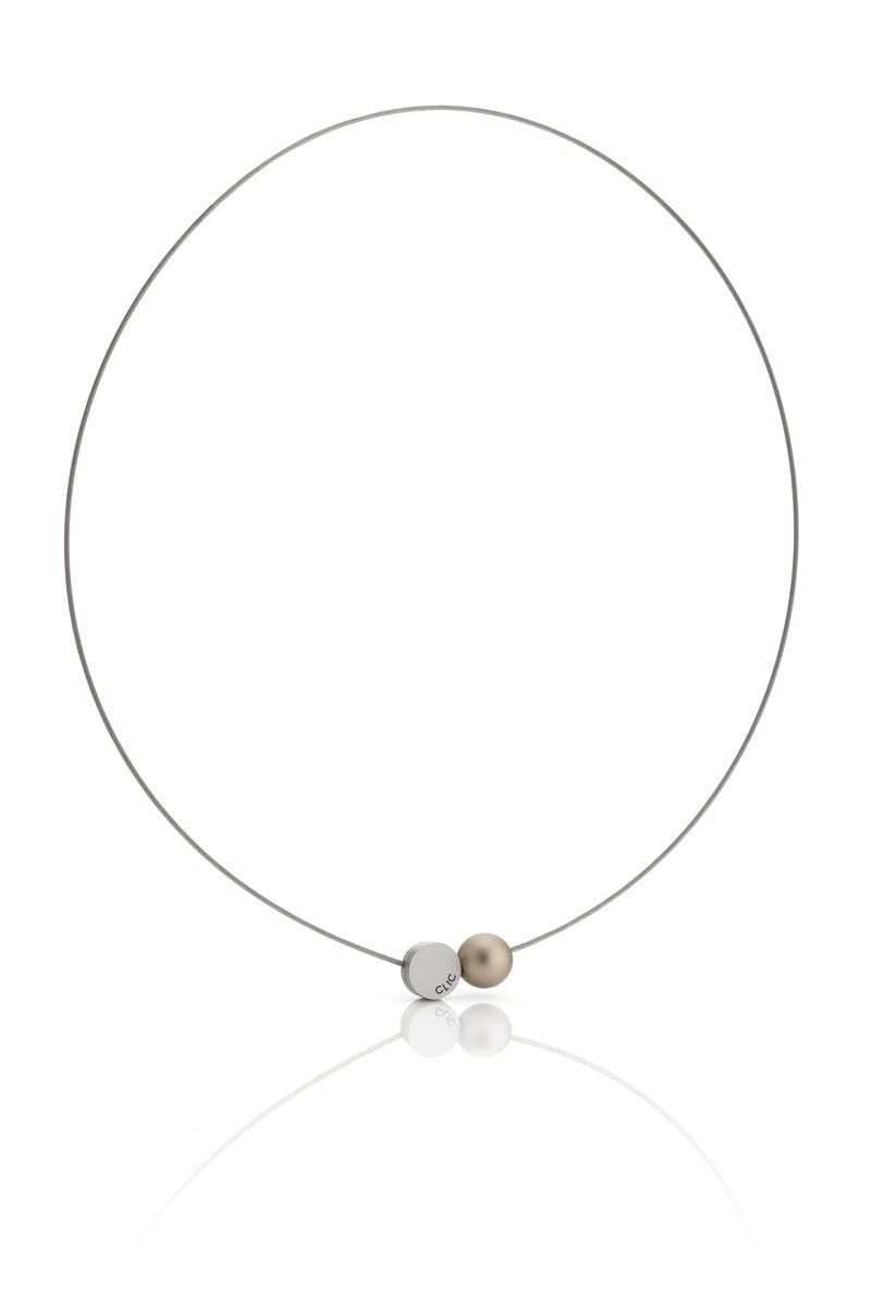 Ervaar de elegantie van de CLIC Creations Collier Mini Kogeltje Goud C192G, handgemaakt in Nederland. Het heeft een minimalistische dunne draadketting met centrale zilveren en parelachtige kralen en een magnetische sluiting, allemaal prachtig weergegeven op een witte achtergrond die de subtiele weerspiegeling vastlegt.