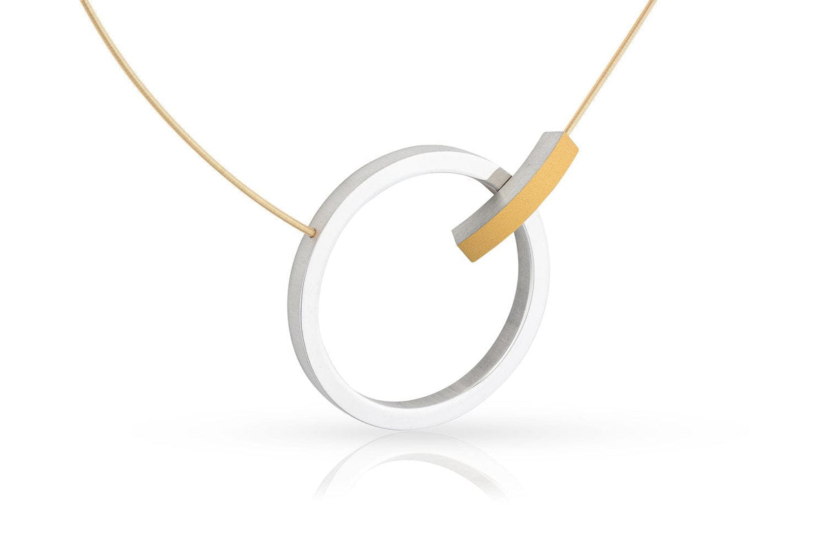 Ontdek de Collier Ring met boogje C249G van CLIC Creations: een moderne ketting met een uniek ontworpen ronde metalen hanger en minimalistische stijl. Handgemaakt in Nederland, met een dunne draad en een klein, gebogen gouden accent, elegant weergegeven op wit met een subtiele schaduw.