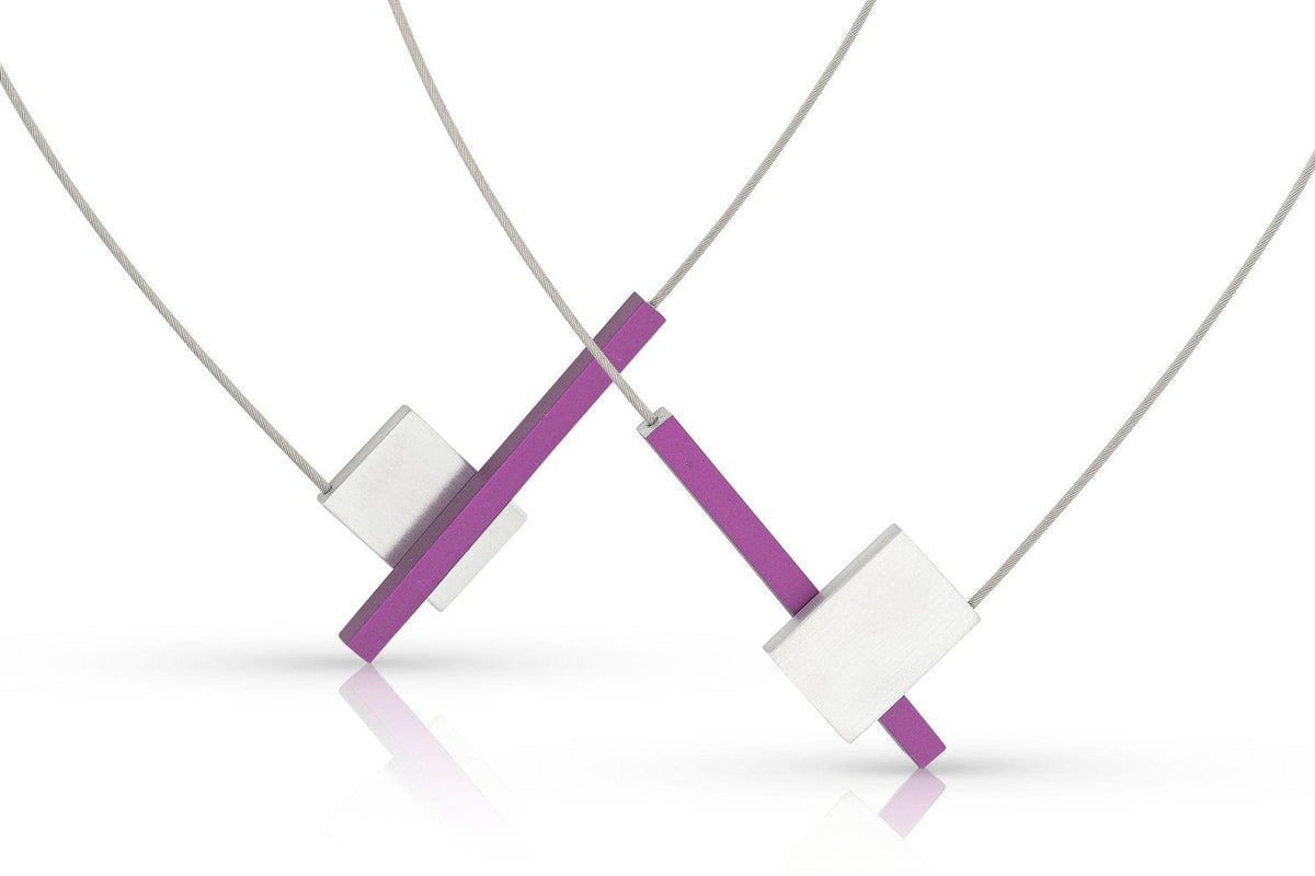 De CLIC Creations Collier V-vorm met staafje C261P bestaat uit twee moderne kettingen met geometrische ontwerpen, die handgemaakt vakmanschap in Nederland laten zien. Ze omvatten een rechthoekig paars segment dat kruist met zilveren vierkanten, opgehangen aan dunne koorden voor een minimalistische look.