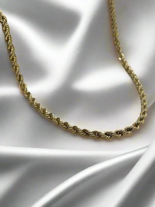 Het vintage gouden collier 14K koord 46cm 3.8gr van Juwelier van der Kooij, met zijn gedraaide touwontwerp, zit elegant op glad wit satijn en contrasteert perfect met het glanzende metaal en de zachte stof - een iconisch stuk uit onze Vintage Collectie.