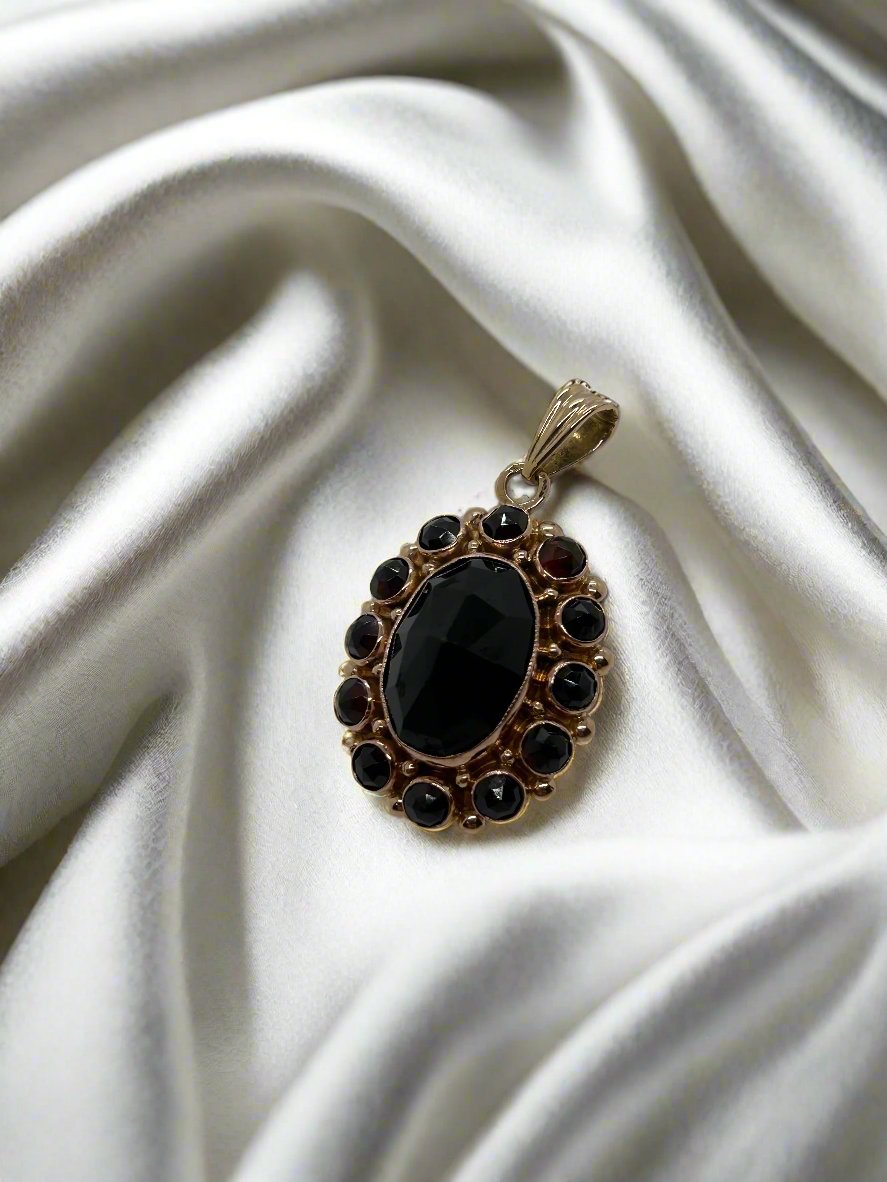 De vintage gouden Hanger 14k van Juwelier van der Kooij toont een elegante granaat ovale edelsteen van 3,6 gram, gevat in een verfijnd ontwerp dat doet denken aan tijdloze allure.