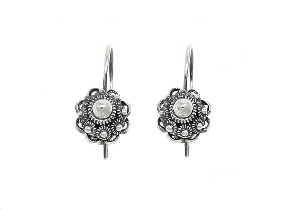 Twee zilveren Zeeuwse Knoop Oorhangers 14mm van Dutch Button met ingewikkelde bloemmotieven en een centrale parel omringd door gedetailleerd kralenwerk, met haakjes om te dragen. De achtergrond is effen wit.
