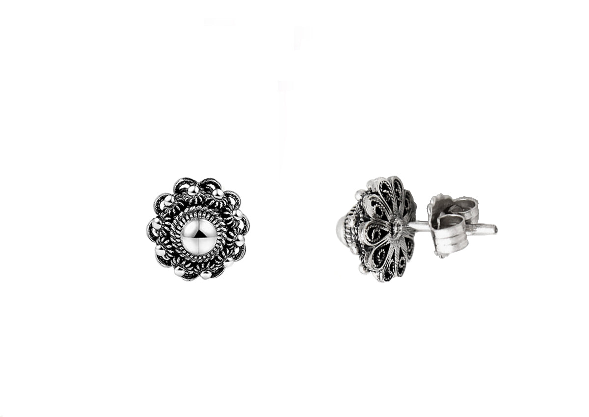 De Zeeuwse Knop Oorstekers 10mm van Dutch Button zijn twee sierlijke oorstekers met een vintage design. Elk heeft een centrale ronde witte parel omringd door ingewikkelde zilveren bloempatronen, afgebeeld op een witte achtergrond met één oorbel naar voren gericht en de andere opzij.