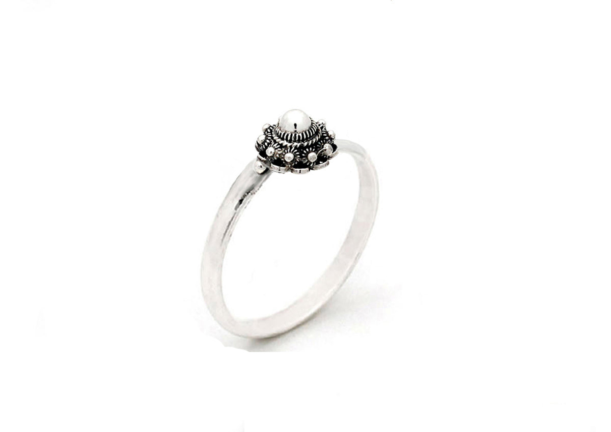 De Zeeuwse Knop Ring Zilver van Dutch Button is een delicate zilveren ring met een ingewikkelde, sierlijke zetting en een kleine parel in het midden, afgebeeld op een effen witte achtergrond.