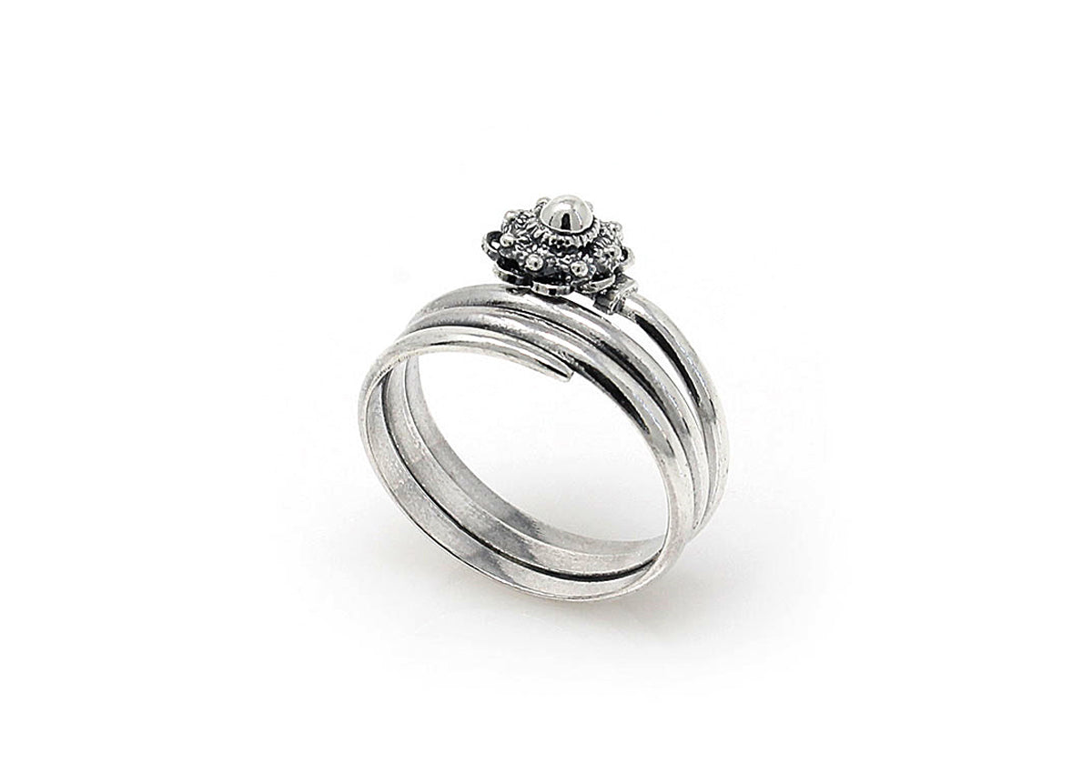 De Dutch Button Zeeuwse Knoop Ring Zilver nr 8 heeft een prominente edelsteen omringd door kleinere stenen in een florale setting. De zilveren band heeft meerdere verweven lagen, vastgelegd tegen een witte achtergrond.