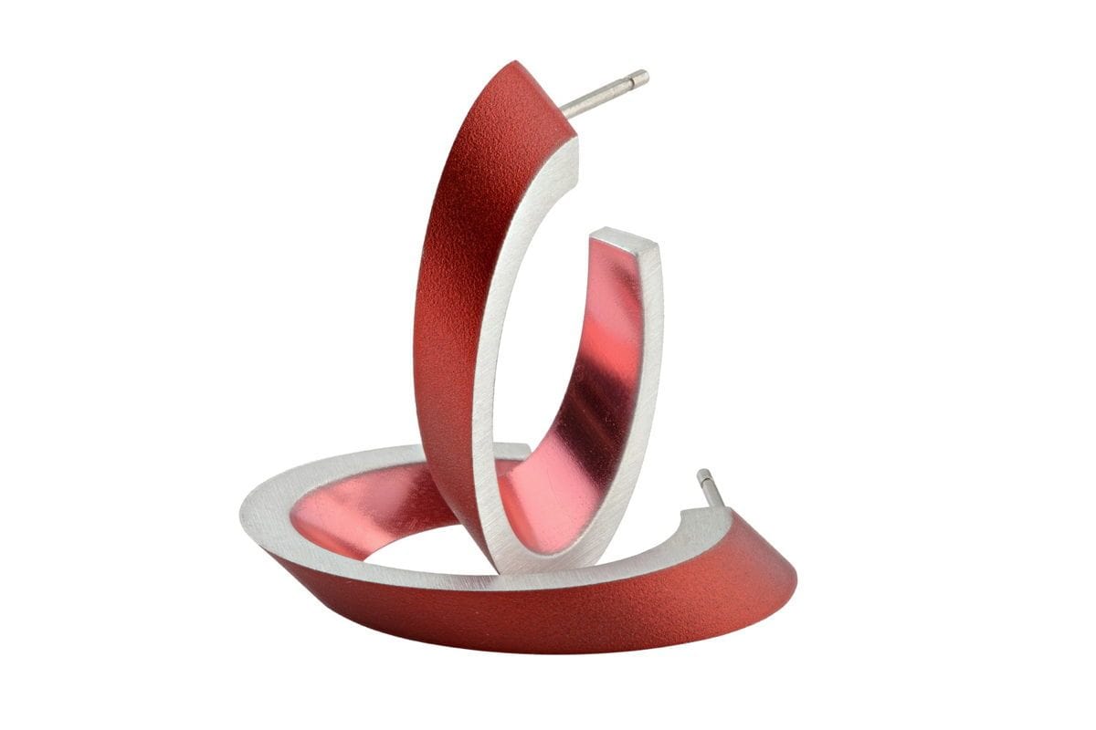 Ovale creolen in rood met een glanzende afwerking en een zilveren rand.
