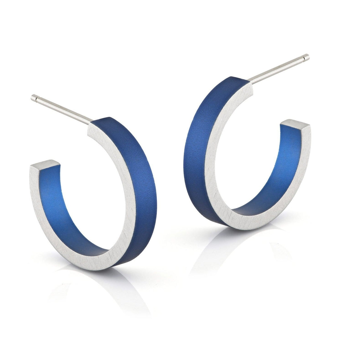 De Creolen Ronde ringetjes Blauw O51B van CLIC Creations zijn uniek ontworpen hypoallergene aluminium oorringen met een zilveren buitenkant en levendig blauwe binnenkant. Deze handgemaakte oorsieraden zijn voorzien van open hoepels en rechte palen, geplaatst tegen een effen witte achtergrond.